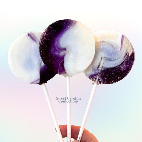 Artisanal marbled purple and white lollipops with blueberry flavor and fine silver edible glitter.