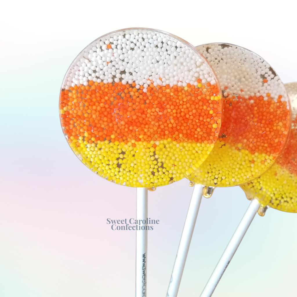 Candy corn Halloween lollipops with white, orange, and yellow layers inside clear sparkle candy from Sweet Caroline Confections.

