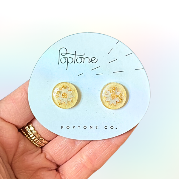 White and yellow daisy flower resin stud earrings shaped like lollipops.