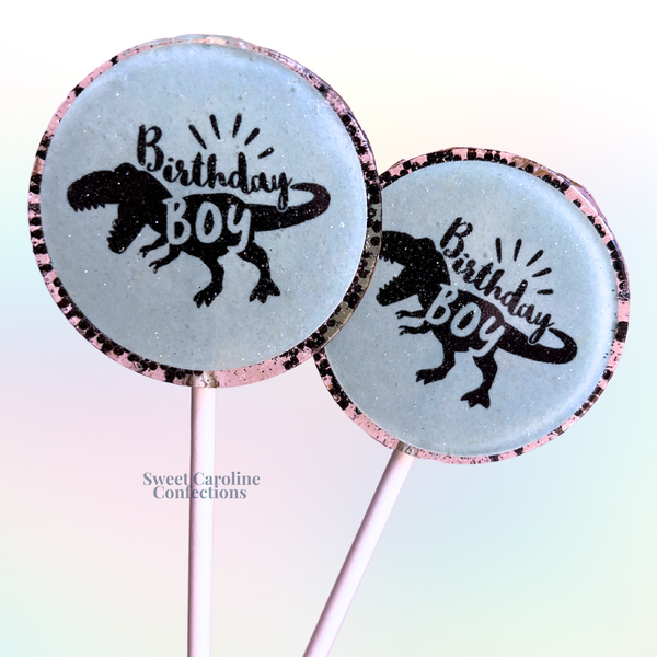 Fun blue lollipops featuring a "Birthday Boy" dinosaur design and edible glitter, perfect for a prehistoric-themed party