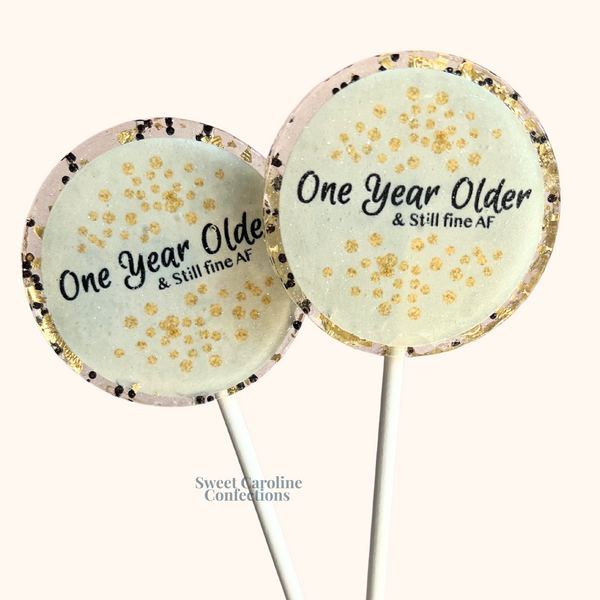 Bold gold and black lollipops with "One Year Older and Still Fine AF" text, a cheeky favor for milestone birthdays.