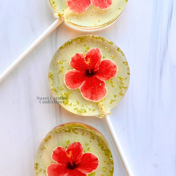 Tropical hibiscus flower lollipops with edible floral designs and signature sparkle by Sweet Caroline Confections.