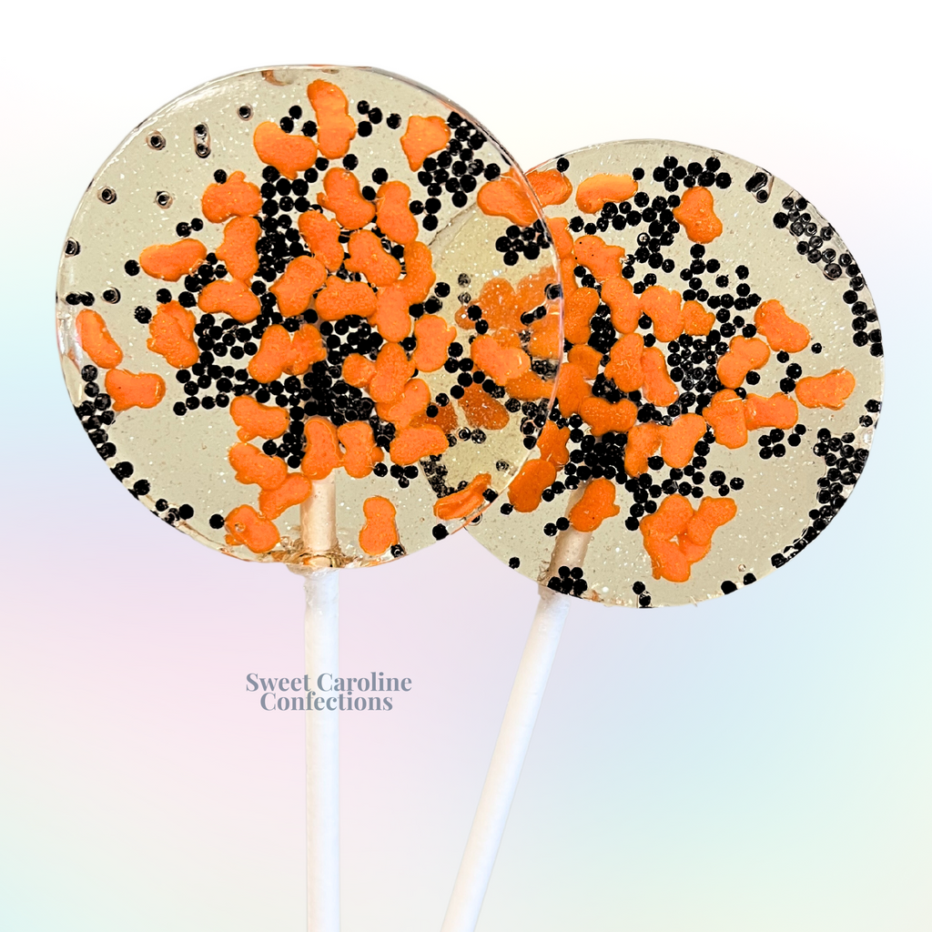 Orange and black tiny pumpkin Halloween lollipops with bright orange pumpkin candies and black sugar crystals from Sweet Caroline Confections.

