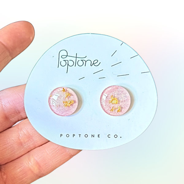 Pink resin lollipop stud earrings with shimmering gold flakes.