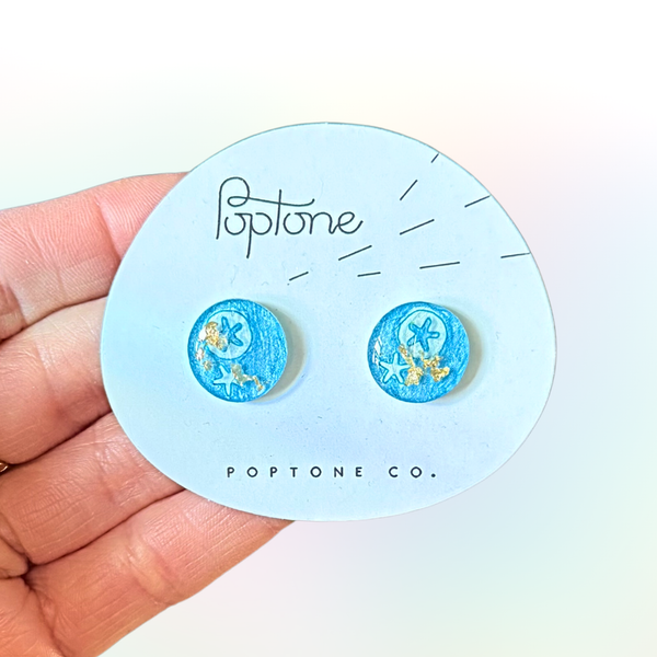 Under the sea themed resin stud earrings shaped like lollipops with teal and purple sparkles.